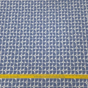May include: Blue and white patterned fabric with a repeating geometric design. The pattern features semi-circles and small dots. A yellow ruler with text is at the bottom of the image.