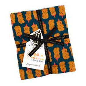 Puede incluir: Un paquete de tela envuelto con una cinta negra y una etiqueta. La tela tiene un fondo verde azulado con un patrón repetido de diseños en forma de oso naranja. La etiqueta tiene texto y un diseño geométrico.