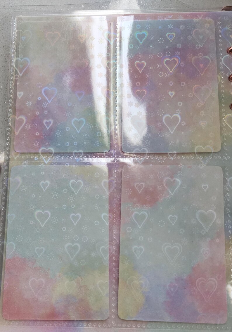 May include: Four clear plastic pockets with a white heart pattern. The pockets are designed to hold cards or other small items.