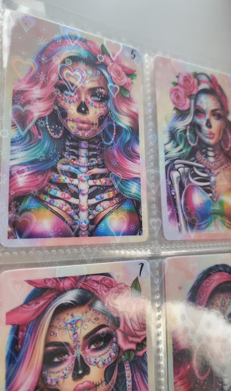 May include: A set of three colorful cards featuring a Day of the Dead theme. Each card has a woman with a sugar skull makeup design, flowers, and a rainbow background. The cards are numbered 5 and 7.