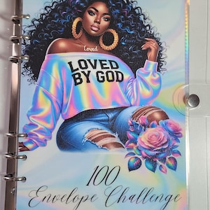 May include: A clear binder with a colorful illustration of a woman wearing a rainbow-colored sweatshirt with the text "LOVED BY GOD." The binder also has the text "100 Envelope Challenge."