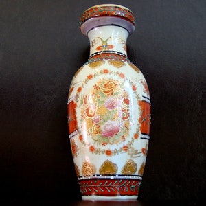 Könnte beinhalten: Eine weiße Keramikvase mit einem Blumendesign in Rot-, Orange- und Goldtönen. Die Vase hat einen runden Körper und einen schmalen Hals.