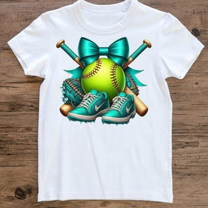 May include: White t-shirt featuring a softball design. The design includes a neon green softball, teal bow, baseball bats, teal baseball glove, and teal sneakers. The softball has brown stitching.