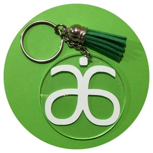 May include: A white logo keychain with a green tassel. The logo is a stylized "a" with a dot above it. The keychain is attached to a silver key ring.