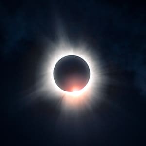 May include: A total solar eclipse with the sun's corona visible as a bright white halo around the dark silhouette of the moon.