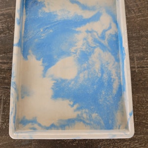May include: A white rectangular tray with a blue marbled design. The tray has a raised rim.