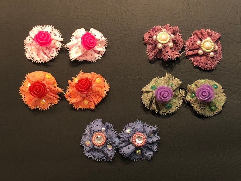 Pu&ograve; includere: Sei paia di fermagli per capelli a forma di fiore di tessuto fatti a mano. I fermagli sono realizzati in pizzo e presentano una variet&agrave; di colori, tra cui rosa, arancione, viola e verde. Ogni fermaglio ha un piccolo fiore al centro.