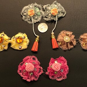 Pu&ograve; includere: Set di sei delicate mollette per capelli in pizzo con vari abbellimenti, tra cui fiori, strass e perle. Le mollette sono disponibili in una variet&agrave; di colori, tra cui rosa, giallo e verde.