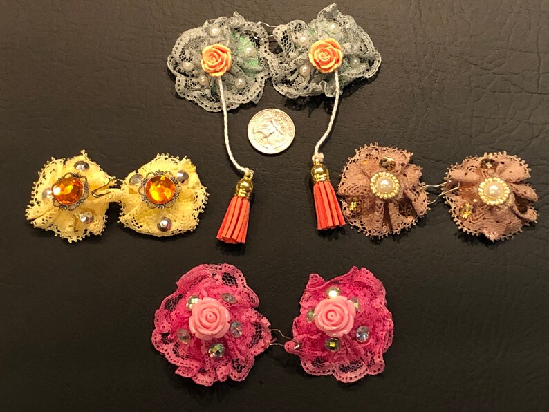 Pu&ograve; includere: Set di sei delicate mollette per capelli in pizzo con vari abbellimenti, tra cui fiori, strass e perle. Le mollette sono disponibili in una variet&agrave; di colori, tra cui rosa, giallo e verde.