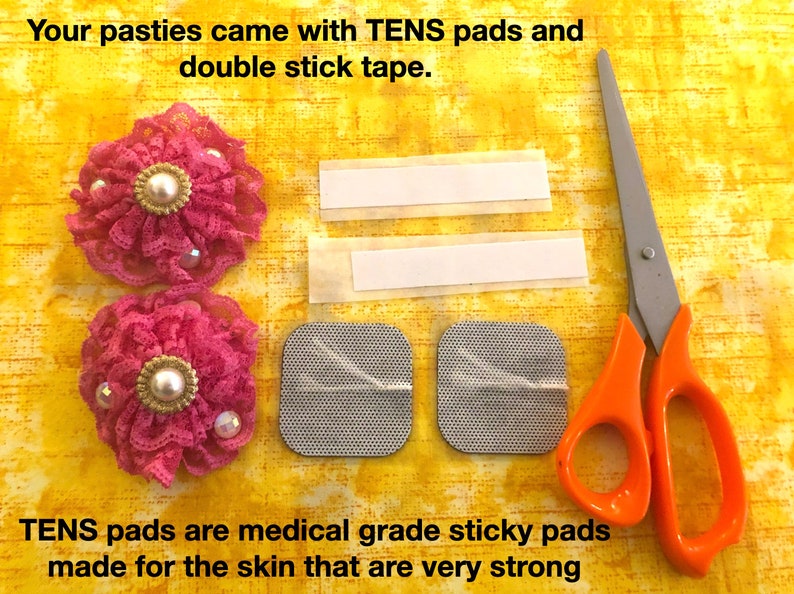 Pu&ograve; includere: Due pasties in tessuto rosa con pizzo e decorazioni di perle, due cuscinetti adesivi TENS, due strisce di nastro biadesivo e un paio di forbici con manici arancioni su uno sfondo di tessuto giallo. "Le tue pasties sono arrivate con cuscinetti TENS e nastro biadesivo." e "I cuscinetti TENS sono cuscinetti adesivi di qualit&agrave; medica realizzati per la pelle che sono molto resistenti" sono scritti in testo nero.