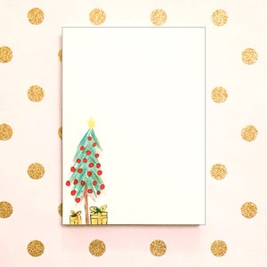 以下が含まれることがあります： 赤いオーナメントと黄色の星がついた緑のクリスマスツリーが描かれた白いカード。ツリーの下には、黄色い包装紙で包まれたプレゼントが2つあります。