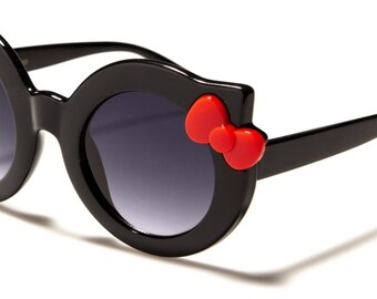 May include: Black cat-shaped sunglasses with red bow accents. The sunglasses have round lenses and a black frame.