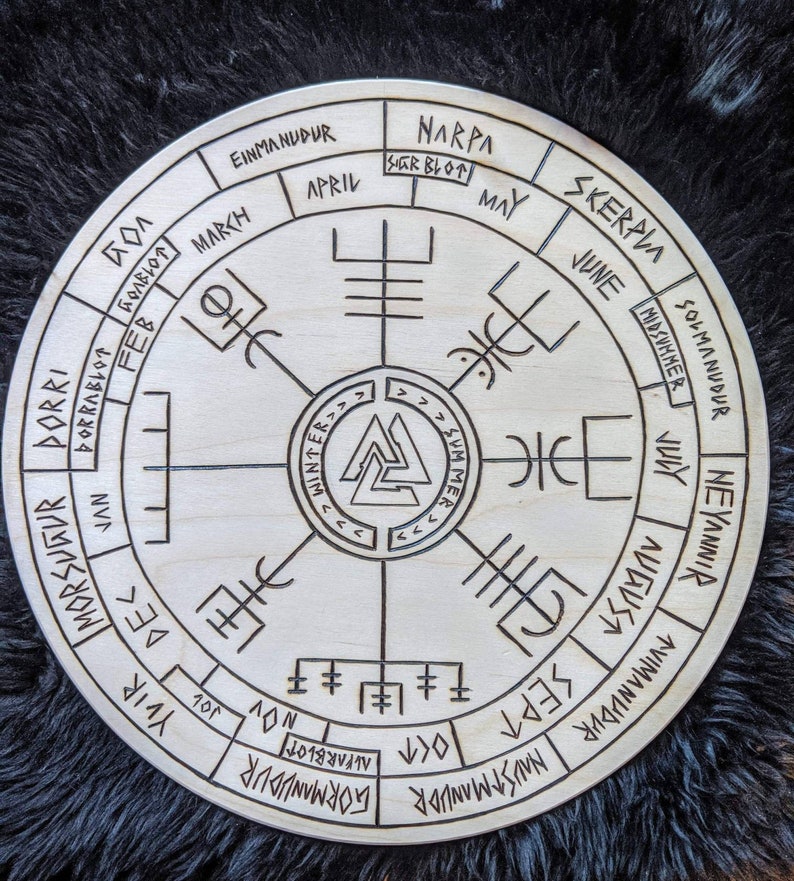 May include: A wooden circular calendar with Norse runes and symbols. The calendar features the months of the year in English and Norse, along with the names of the Norse holidays. The calendar is divided into four sections representing the seasons: winter, spring, summer, and fall.