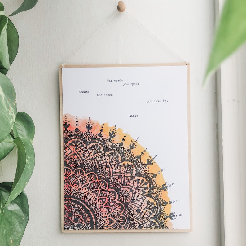 May include: A motivational quote printed on a white background with a colorful mandala design in the bottom left corner. The quote reads: "The words you speak become the house you live in. -Hafiz"