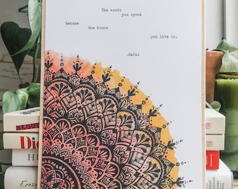 Puede incluir: Una impresión de acuarela con un diseño de mandala en blanco y negro. La impresión presenta una cita de Hafiz: "Las palabras que dices se convierten en la casa en la que vives."