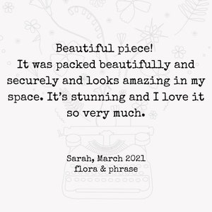 May include: A black and white image of a typewriter with a customer review that reads "Beautiful piece! It was packed beautifully and securely and looks amazing in my space. It's stunning and I love it so very much." The review is signed "Sarah, March 2021 flora & phrase".