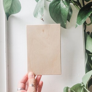 May include: A light brown wooden board, held in a hand, against a white background.