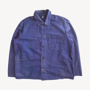 May include: A vintage blue work jacket with a vertical striped pattern. The jacket features a collared neckline, button-down closure, and multiple front pockets. The jacket is made of a durable fabric, and has a worn appearance.