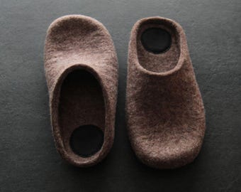 May include: A pair of brown felt slippers with a black felt lining. The slippers are soft and comfortable, perfect for wearing around the house.