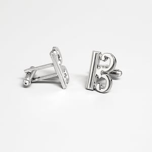 May include: A pair of silver cufflinks featuring the treble clef symbol. The cufflinks are designed with a classic, elegant style.