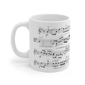 May include: White ceramic mug with a black and white musical score printed on the side. The score includes musical notes, clefs, and markings such as "sul C", "p ad lib.", "mf", and "allarg."