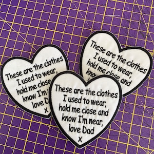 May include: Three heart-shaped patches with black edging and white fabric. Each patch features embroidered text: "These are the clothes I used to wear, hold me close and know I'm near, love Dad X."
