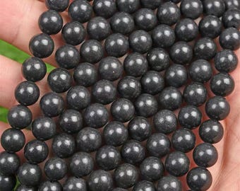 Op de afbeelding: Een streng zwarte ronde kralen, gemaakt van natuursteen, voor het maken van sieraden.