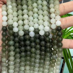 May include: A strand of round, green and white jade beads. The beads are graduated in color, with the lightest beads at the top and the darkest beads at the bottom.