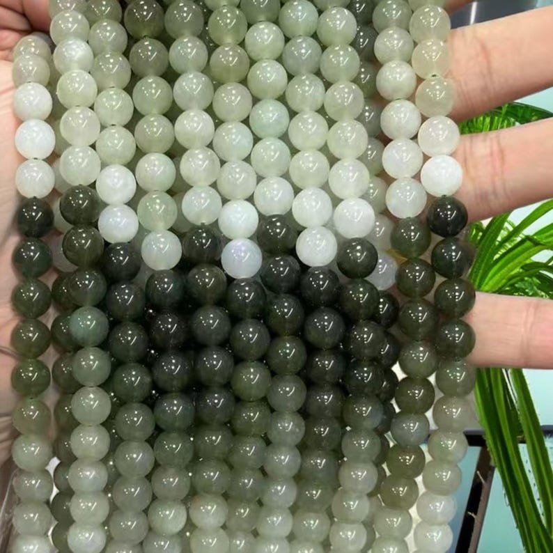 May include: A strand of round, green and white jade beads. The beads are graduated in color, with the lightest beads at the top and the darkest beads at the bottom.