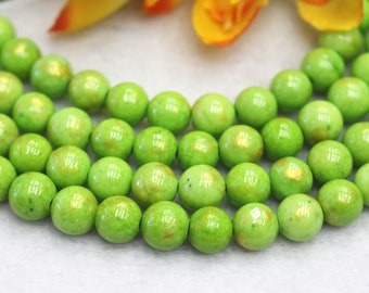 May include: A strand of green and gold beads. The beads are round and have a glossy finish.