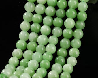 May include: Close-up of a strand of light green jade beads. The beads are round and smooth, with a slight variation in colour. The beads are strung together, creating a necklace or bracelet.