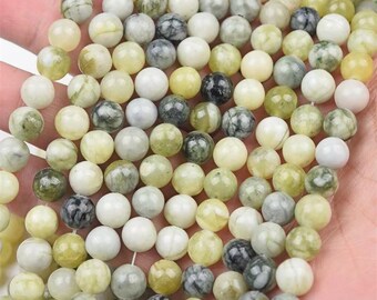 May include: A collection of round beads in various shades of green, white, and gray. The beads have a polished, smooth surface and are strung together. The color variations create a natural, earthy aesthetic, suitable for jewelry making or craft projects.