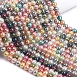 Può includere: Un filo di perle multicolori. Le perle sono rotonde e hanno una finitura liscia e lucida. I colori includono bianco, crema, rosa, verde, blu e nero.