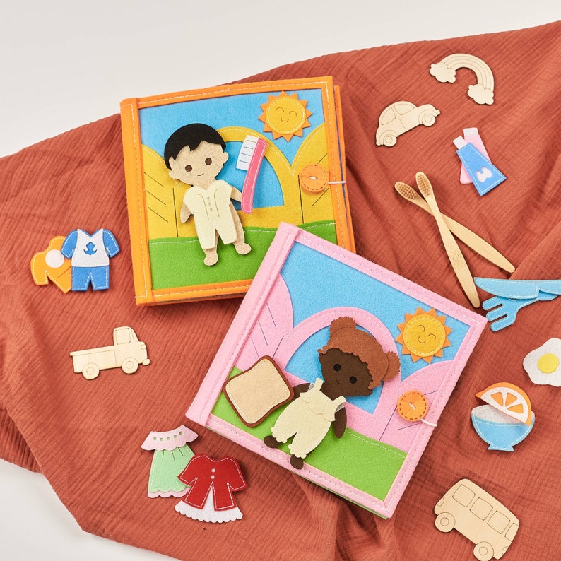 May include: Two felt books with different characters and scenes. The first book features a boy with a toothbrush and the second book features a girl with a slice of bread. Both books have a colorful design with felt details.