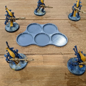 May include: A set of five gray plastic miniature figure bases. The bases are arranged in a cloud shape and are designed to hold miniature figures.
