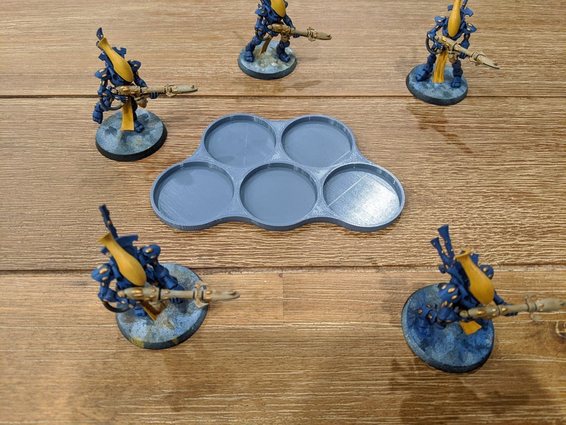 May include: A set of five gray plastic miniature figure bases. The bases are arranged in a cloud shape and are designed to hold miniature figures.