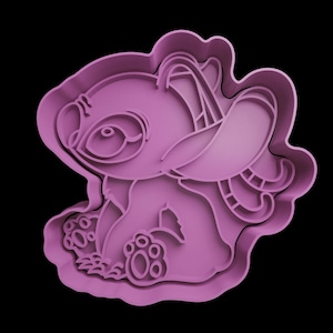 May include: A pink plastic cookie cutter shaped like the Disney character Stitch. The cutter depicts Stitch seated, with his large ears, eyes, and paws. The cutter is set against a black background.