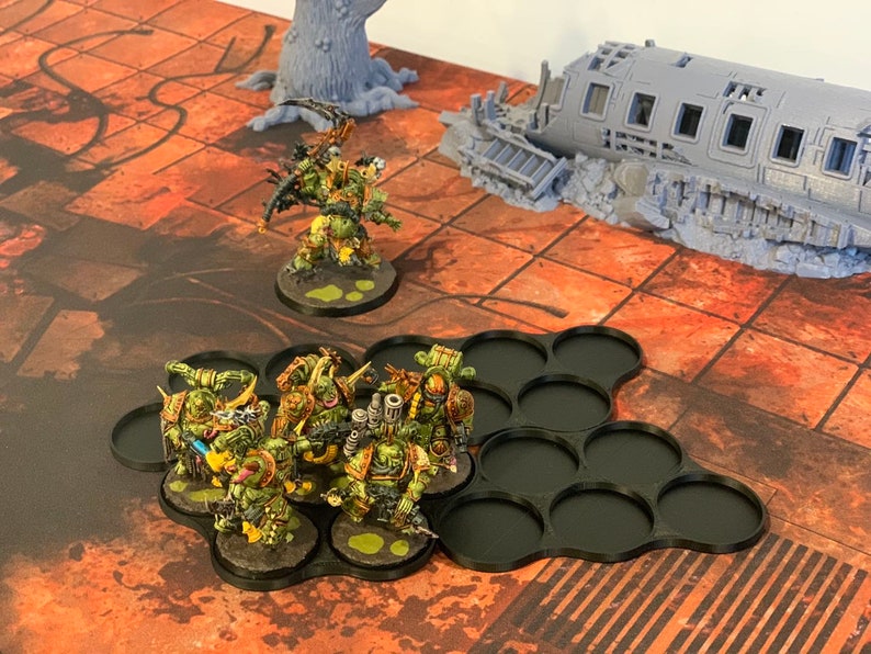 May include: A group of green and yellow painted miniature figures on black circular bases, arranged in a hexagonal pattern. The figures are standing on a red and brown tiled surface.