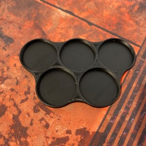 May include: Black plastic tray with six round compartments. The tray is designed to hold miniature figures or other small objects.