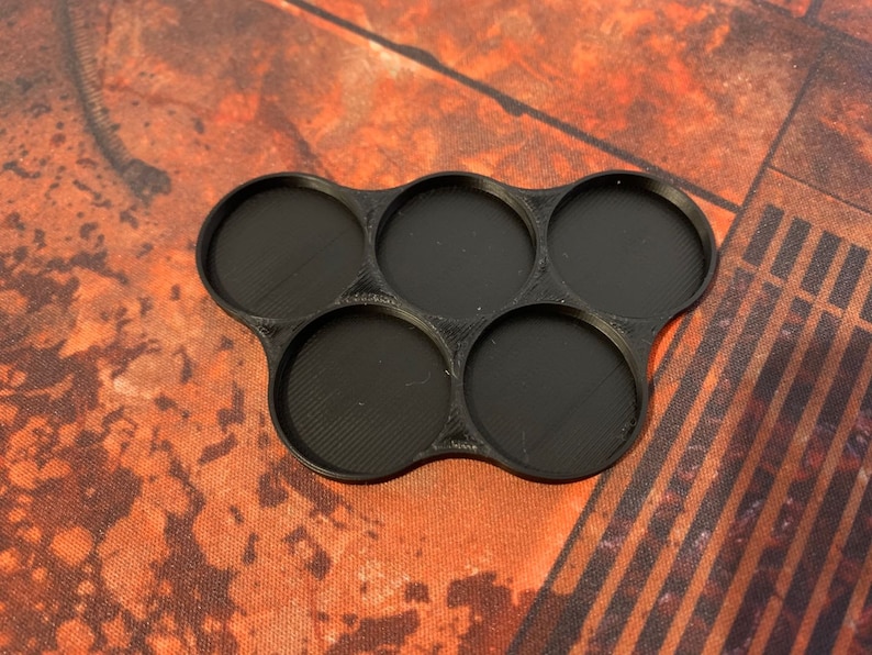 May include: Black plastic tray with six round compartments. The tray is designed to hold miniature figures or other small objects.