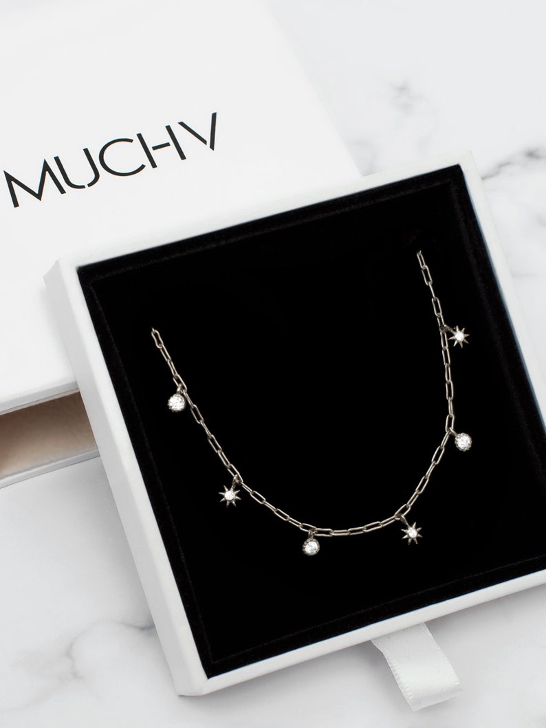 Sterling silver paperclip chain necklace for layering with six tiny moon and star charms.