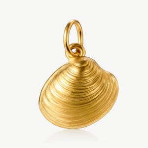 May include: A gold-toned pendant shaped like a clam shell with a textured, ridged surface and a smooth, rounded bail at the top for attachment. The piece features a metallic finish that reflects light, highlighting the concentric shell ridges.