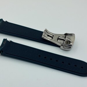 May include: A dark blue watch strap with a silver buckle. The strap has a textured surface and is made of rubber.