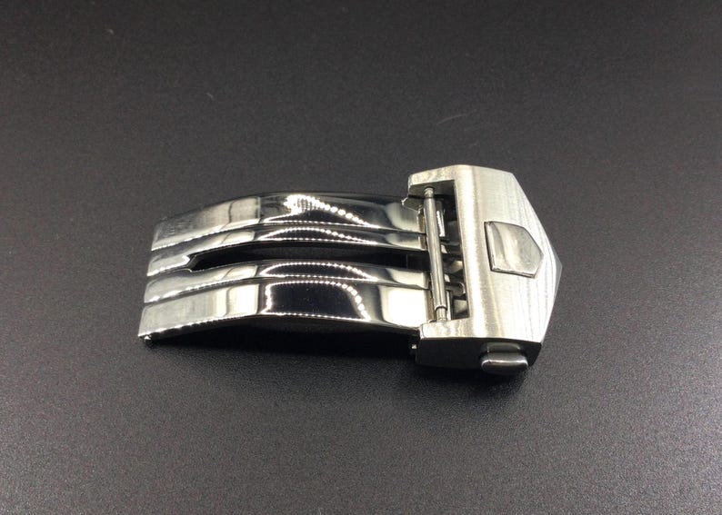 May include: A silver metal watch band clasp with a polished finish and a push-button release.