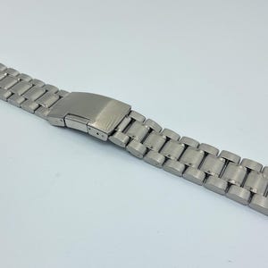 May include: A silver metal watch band with a clasp.