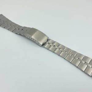 Peut inclure: Un bracelet de montre en métal argenté avec une finition brossée.