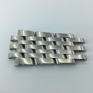 Könnte beinhalten: Ein silbernes Armband mit gewebtem Muster.
