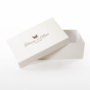 Pode incluir: Uma caixa branca com um logotipo de borboleta marrom e o texto "House of Elliot - England". A caixa est&aacute; aberta e a tampa est&aacute; inclinada para o lado.