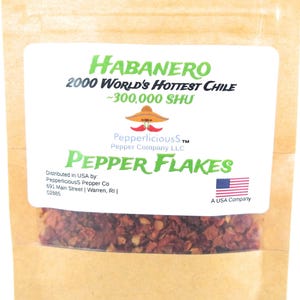 May include: A brown paper pouch with a white label that reads "HABANERO 2000 WORLD'S HOTTEST CHILE ~300,000 SHU PepperliciousS TM Pepper Company LLC PEPPER FLAKES Distributed in USA by: PepperliciousS Pepper Co 691 Main Street | Warren, RI | 02885 A USA Company". The pouch contains red pepper flakes.