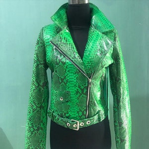 May include: A green snakeskin leather jacket with a zip fastening and a belt. The jacket has a stand-up collar and long sleeves.